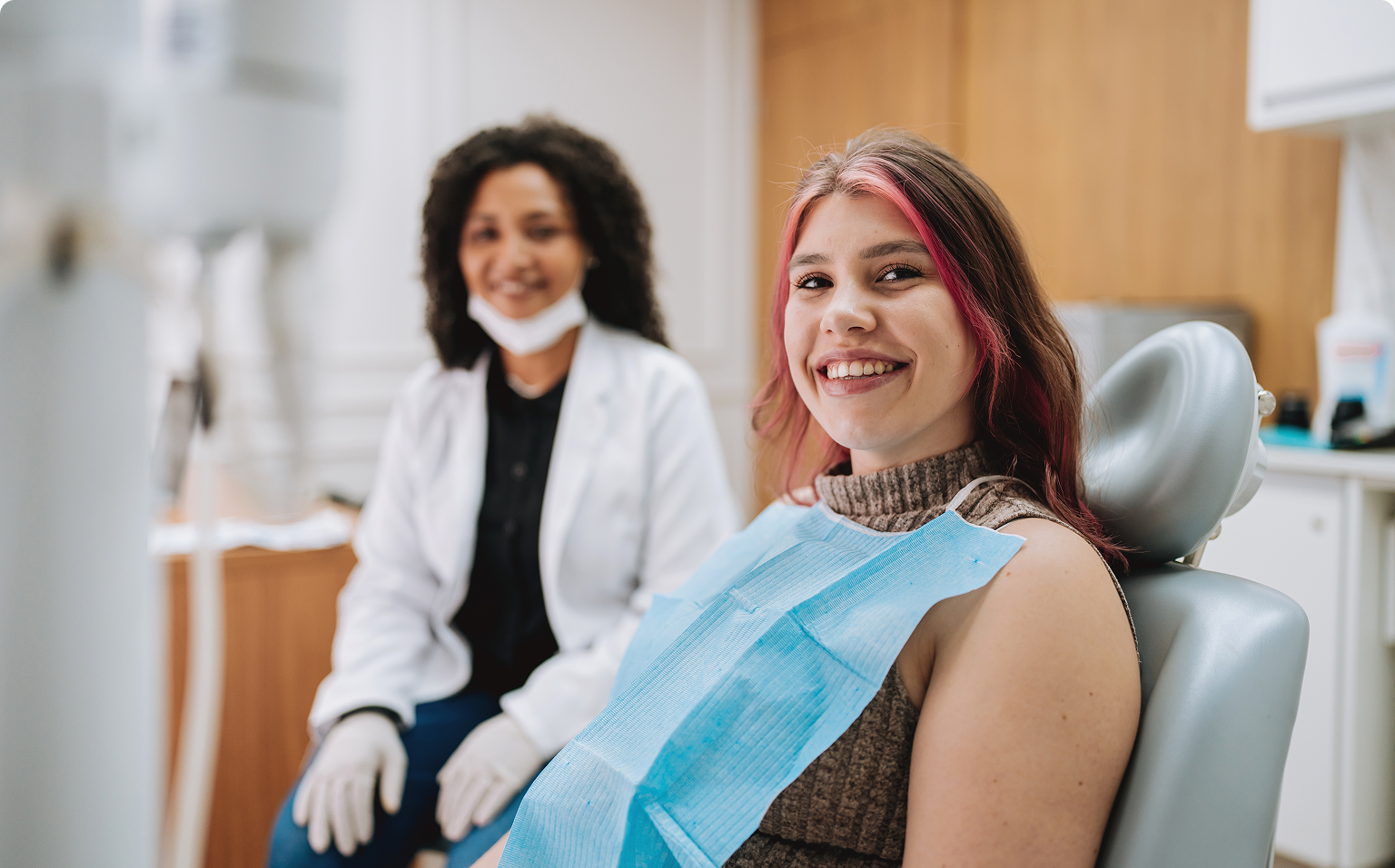 Smiling woman at dentist office with dentist.